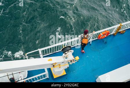 Frau mit Rucksack, die die Nordseelandschaften auf der norwegischen Fähre während der Fahrt von Dänemark aus genießt. Die Szene fängt das Wesen von entspanntem Reisen ein, Exploration i Stockfoto