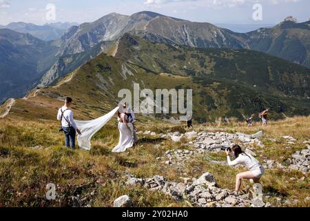 Frisch vermählte machen am letzten Wochenende der Schulferien eine Fotosession auf dem Gipfel des Kasprowy Wierch in der Tatra in Südpolen. Die Berge des Tatra-Nationalparks sind sehr überfüllt. Touristen warten manchmal in einer Warteschlange, um einen Gipfel zu erreichen. Stockfoto