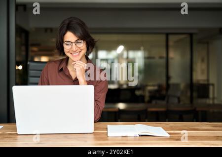 Junge glückliche Geschäftsfrau, die im Büro am Computer arbeitet. Stockfoto