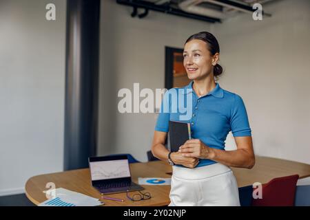 Eine professionelle Frau, die in einem Büro arbeitet und gleichzeitig ein Notebook und ein Notebook für Aufgaben verwendet Stockfoto