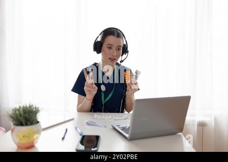 Junge schöne Ärztin, die Kopfhörer trägt, Online-Webcam-Videoanrufe auf Laptop-Bildschirm macht und dem Patienten Ratschläge gibt. VideoCall-Ansicht. Tele-me Stockfoto