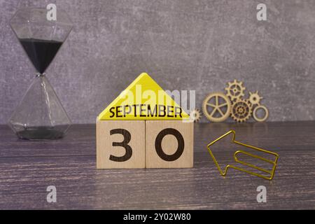 September 30 auf einem Holzkalender neben dem Wecker. September-Tag, leerer Platz für Text. Kalender für September auf hellem Hintergrund Stockfoto