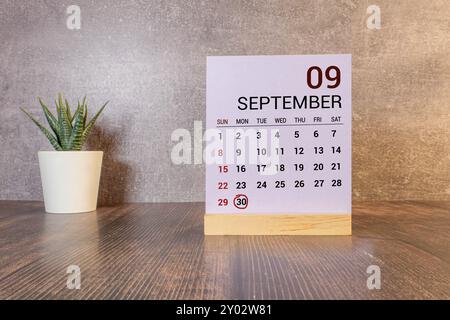 September 30 auf einem Holzkalender neben dem Wecker. September-Tag, leerer Platz für Text. Kalender für September auf hellem Hintergrund Stockfoto