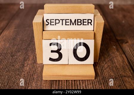 September 30 auf einem Holzkalender neben dem Wecker. September-Tag, leerer Platz für Text. Kalender für September auf hellem Hintergrund Stockfoto