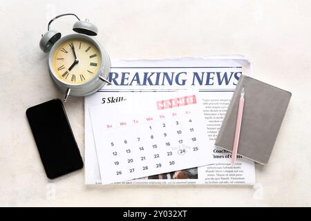 Tageszeitung mit Kalender, Wecker und Mobiltelefon auf weißem Tisch. Black Friday-Angebot Stockfoto