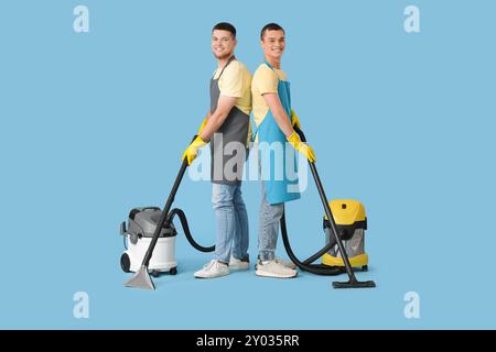 Männliche Hausmeister mit Staubsaugern auf blauem Hintergrund Stockfoto