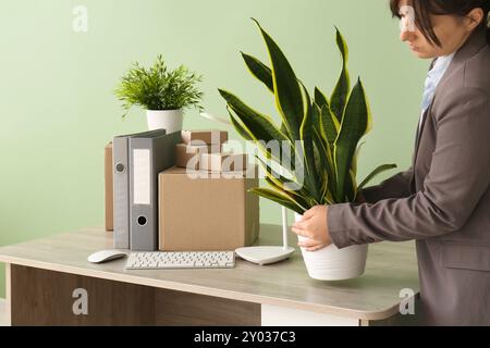 Geschäftsfrau, die am Umzugstag Pflanzen vom Schreibtisch im Büro nimmt Stockfoto