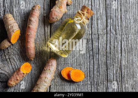 Glasflasche mit ätherischem Kurkuma - Öl mit Kurkuma - Wurzeln auf hölzernem Hintergrund ( curcuma longa ) Stockfoto