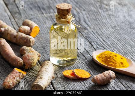 Glasflasche mit ätherischem Kurkuma - Öl mit Kurkuma - Wurzeln auf hölzernem Hintergrund ( curcuma longa ) Stockfoto