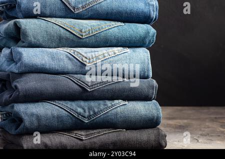 Stack aus verschiedenen Jeans, Hosen auf rustikalem Steinhintergrund, Modedesign Stockfoto