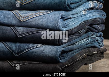 Stack aus verschiedenen Jeans, Hosen auf rustikalem Steinhintergrund, Modedesign Stockfoto