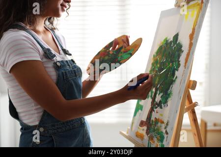 Frau, die ein Bild mit einem Palettenmesser im Atelier zeichnet, Großaufnahme Stockfoto