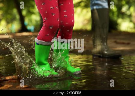 Mutter und Tochter tragen Gummistiefel, stehen draußen in der Pfütze, Nahaufnahme Stockfoto