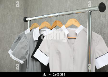 Die Uniformen der Zimmermädchen auf dem Kleiderständer in der Nähe der grauen Wand Stockfoto