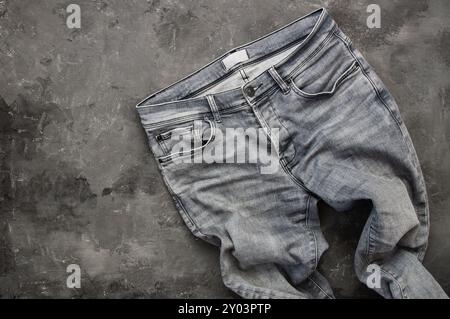 jeans aus grauem Denim, Hose auf rustikalem Steinhintergrund, Modedesign Stockfoto