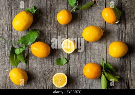 Frische reife gelbe Zitronenfrüchte mit Blättern auf hölzernem Hintergrund Stockfoto