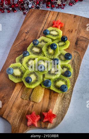 Obstweihnachtsbaum aus Kiwis, Heidelbeeren und Wassermelone auf einer Holzplatte Stockfoto