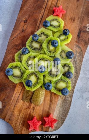 Obstweihnachtsbaum aus Kiwis, Heidelbeeren und Wassermelone auf einer Holzplatte Stockfoto