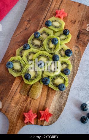 Obstweihnachtsbaum aus Kiwis, Heidelbeeren und Wassermelone auf einer Holzplatte Stockfoto