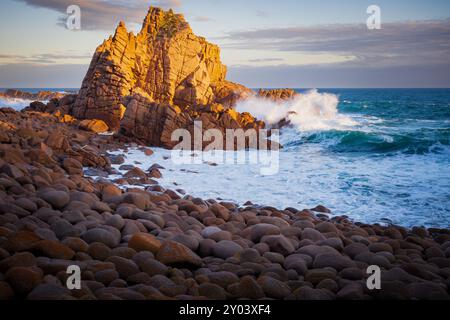 Wellen brechen bei Sonnenschein am späten Nachmittag auf einer großen Felsformation auf den Pinnacles auf Phillip Island im Süden von Victoria, Australien Stockfoto