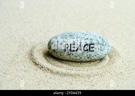 Friedenstext auf Stein mit Sandstrand-Hintergrund. Beruhigendes Konzept. Stockfoto