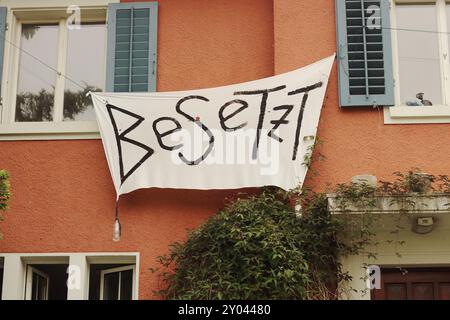 Die Fassade eines besetzten Gebäudes in Zürich zeigt ein markantes Besetz-Banner, das das komplexe Zusammenspiel von Besetzung, Anarchie und alternativem li symbolisiert Stockfoto