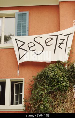 Die Fassade eines besetzten Gebäudes in Zürich zeigt ein markantes Besetz-Banner, das das komplexe Zusammenspiel von Besetzung, Anarchie und alternativem li symbolisiert Stockfoto