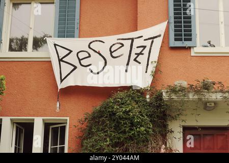 Die Fassade eines besetzten Gebäudes in Zürich zeigt ein markantes Besetz-Banner, das das komplexe Zusammenspiel von Besetzung, Anarchie und alternativem li symbolisiert Stockfoto