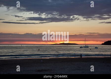 Ein roter Sonnenuntergang über Playa América in Nigrán, Spanien, mit der Silhouette der Las Estelas Inseln im Hintergrund. Der Himmel ist in tiefen Tönen gemalt Stockfoto