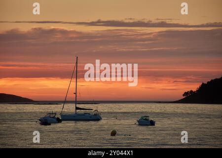 Ein roter Sonnenuntergang über Playa América in Nigrán, Spanien, mit der Silhouette der Las Estelas Inseln im Hintergrund. Der Himmel ist in tiefen Tönen gemalt Stockfoto