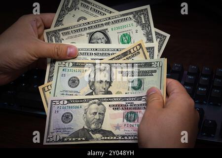 Shanghai, China. 31. August 2024. In dieser Abbildung hält eine Person einige US-Dollar-Barscheine in der Hand, von denen einige auf einem Tisch liegen. (Foto: Sheldon Cooper/SOPA Images/SIPA USA) Credit: SIPA USA/Alamy Live News Stockfoto