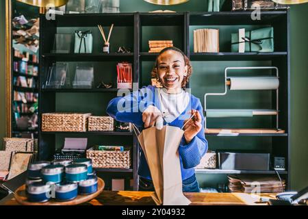 Porträt einer glücklichen Frau, die Papiertüte hält, während sie an der Kasse im Laden steht Stockfoto