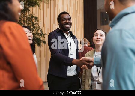 Glücklicher männlicher Unternehmer beim Handschlag mit dem Teilnehmer während des Seminars im Kongresszentrum Stockfoto