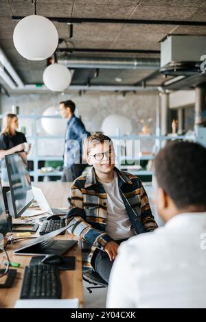 Junger männlicher Unternehmer im Gespräch mit Kollegen im Tech-Startup-Büro Stockfoto