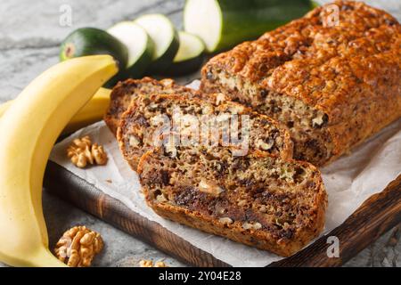 Hausgemachtes glutenfreies Zucchini-Bananenbrot mit Walnüssen und dunkler Schokolade auf Holzbrett auf dem Tisch. Horizontal Stockfoto