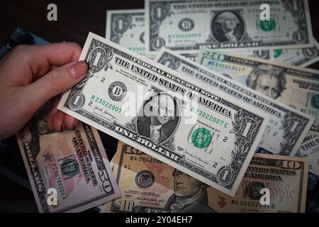Shanghai, China. 31. August 2024. In dieser Abbildung hält eine Person einige US-Dollar-Barscheine in der Hand, von denen einige auf einem Tisch liegen. Quelle: SOPA Images Limited/Alamy Live News Stockfoto