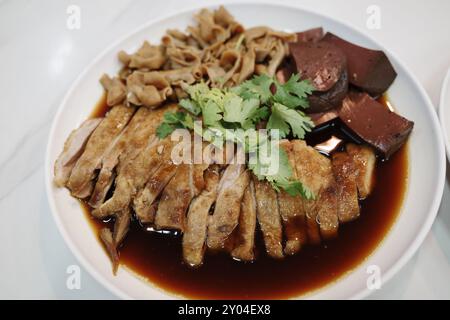 Eine Nahaufnahme eines traditionellen asiatischen Gerichts mit zarter, in Scheiben geschmorter Ente, die auf einem weißen Teller angeordnet ist. Stockfoto