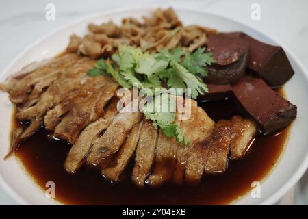 Eine Nahaufnahme eines traditionellen asiatischen Gerichts mit zarter, in Scheiben geschmorter Ente, die auf einem weißen Teller angeordnet ist. Stockfoto