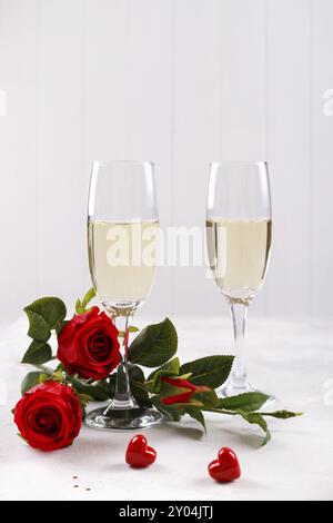 Zwei Sektgläser, rote Rosen und Geschenkbox, romantischer Hintergrund. Vertikal Stockfoto