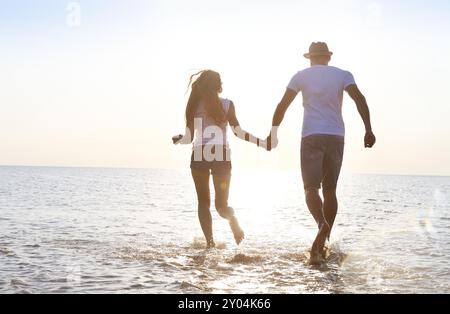 Glückliche junge Paare, die Spaß am Strand bei Sonnenuntergang laufen. Reisen-Konzept Stockfoto