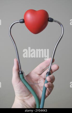 Des Menschen Hand hält ein rotes Herz und Stethoskop Stockfoto