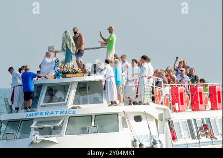 Rom, Italien. 31. August 2024. Ein Fischer huldigt der Madonna, nachdem er den Ring anläßlich der Hochzeit mit dem Meer von Ostia in Rom auf die Hände gelegt hat. Auch in diesem Jahr fand die traditionelle „Hochzeit mit dem Meer“ im Rahmen der Madonna della Stella Maris im Fischerdorf Ostia in Rom statt. Stella Maris ist einer der ältesten Titel, die mit der Madonna als Zeichen der Hoffnung verbunden sind, als Nordstern für Christen, genannt als Beschützer derer, die auf dem Seeweg reisen. In Ostia soll die Hommage an die Madonna auch ein Dankeschön für den Fang sein, den sie hat Stockfoto