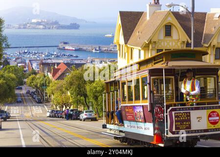 San Francisco, USA, 10. Mai 2016: Bremsassistenten-Seilbahnbremsen fahren bergab auf dem steilen Hügel der Hyde Street mit einem atemberaubenden Blick auf das Alcatraz Prison, BA Stockfoto