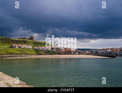 Ein sonnendurchfluteter Tatehill-Strand, Cottages und Häuser in Whitby saßen alle unter einem grauen bedeckten Himmel. Stockfoto