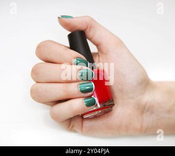 Maniküre. Schönheitsbehandlungsfoto einer schön gepflegten Frau mit Fingernägeln mit rotem nagellack. Feminine Nailart mit schönem Glitzer, grüner und weißer Nai Stockfoto