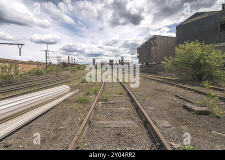 Verlassene Bahngleise in einem Industriewerk, umgeben von Vegetation und Industriegebäuden, Stahlwerk HF4, Lost Place, Dampremy, Charleroi, P Stockfoto
