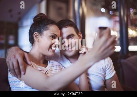 Junge Frau, die ein Foto mit ihrem Handy in einem Café. Glückliches junges Paar Selfie zu tun Stockfoto