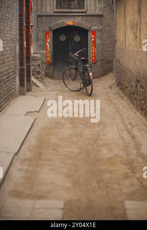 Ein Fahrrad parkt in einer alten Gasse in der historischen ummauerten Stadt Pingyao, China, Asien Stockfoto