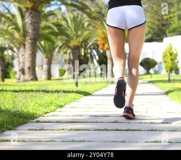 Lauffüße laufen auf der Straße im Park. CCloseup auf Schuhen. Woman Fitness Sonnenaufgang Jog Workout Welness Konzept Stockfoto