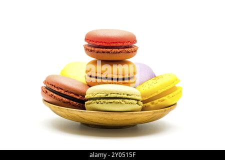 Süße bunte Macarons in Holzplatte auf weißem Hintergrund Stockfoto